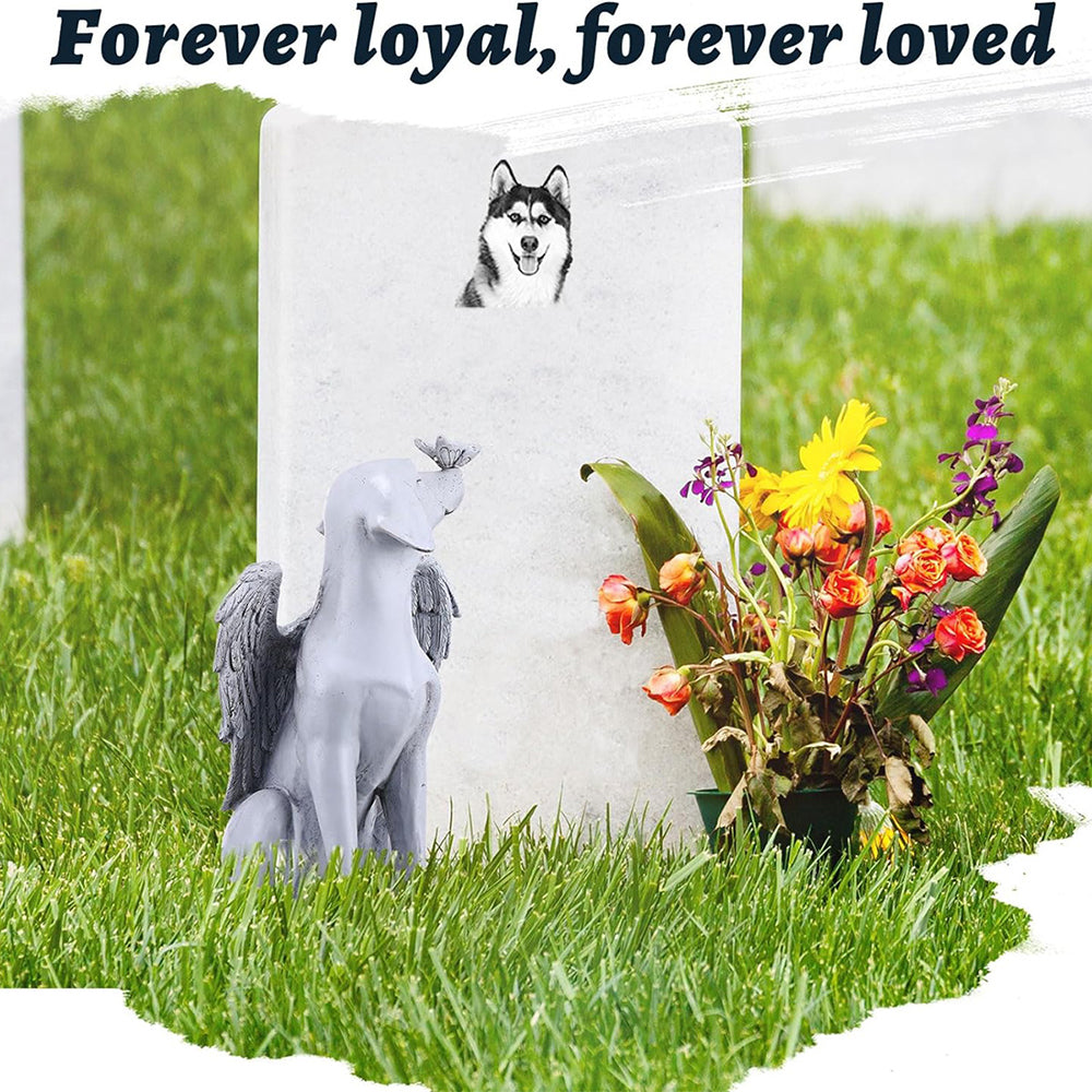 Pet memorial statue beside flowers and a remembrance marker